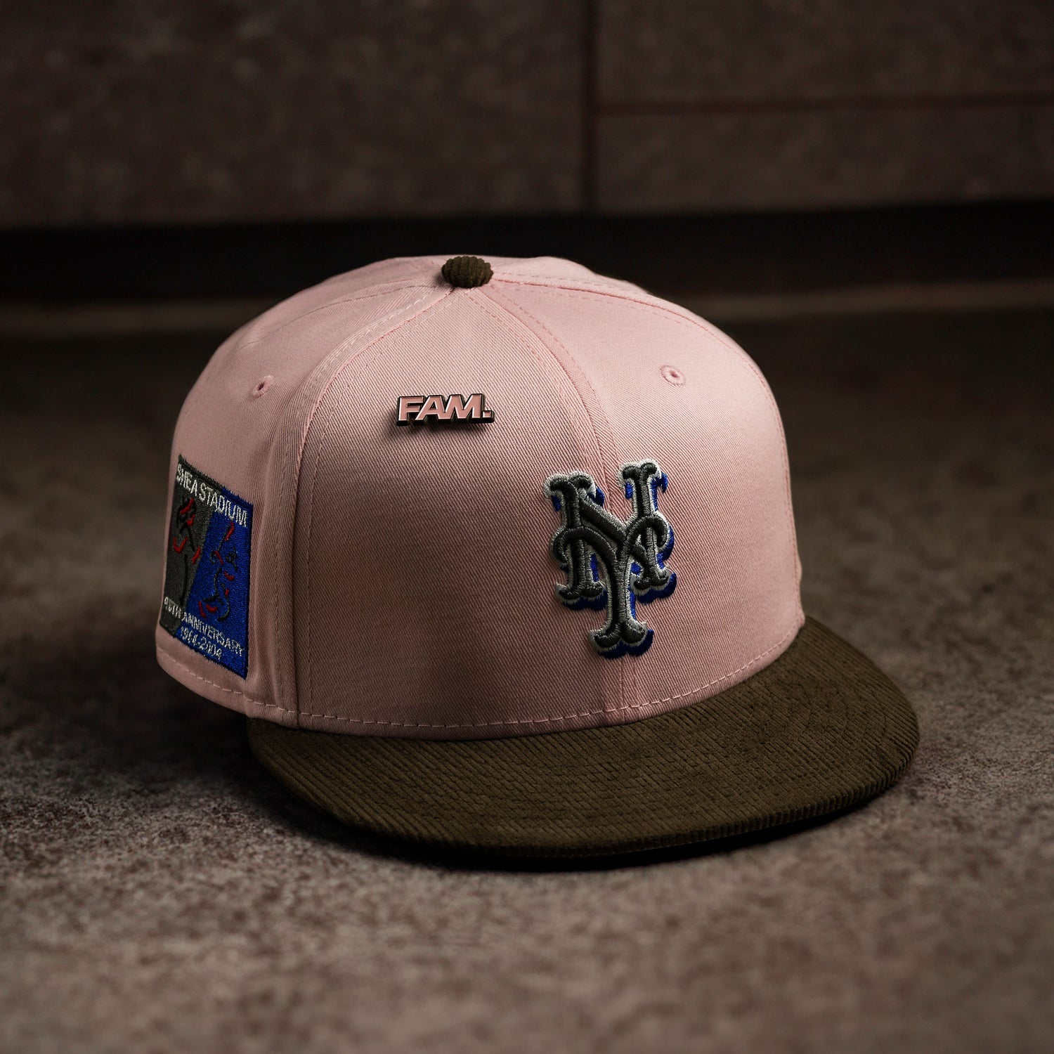 Pink and brown baseball cap with logo and patch on a textured surface