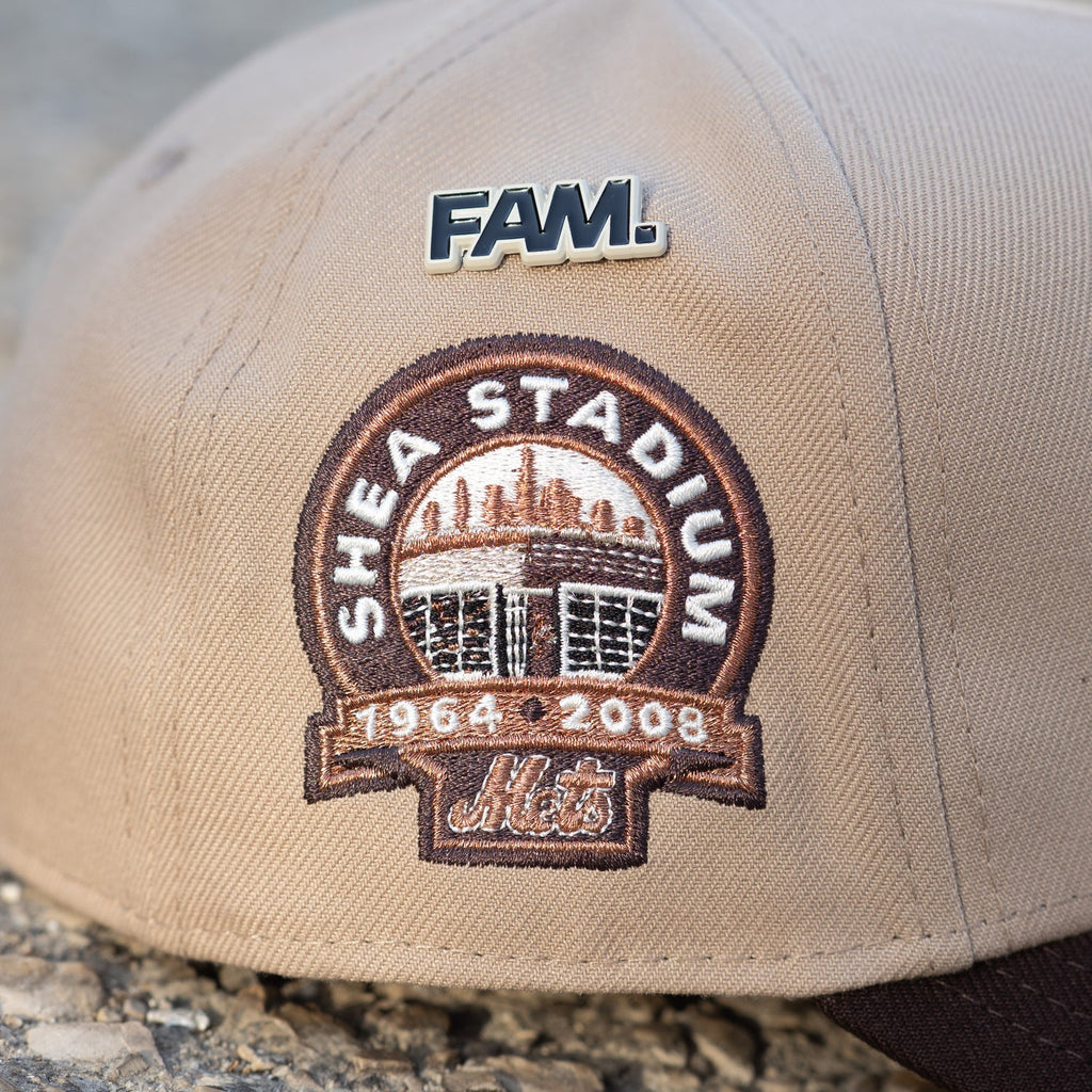 Beige cap with Shea Stadium patch and 'FAM' logo on a stone surface